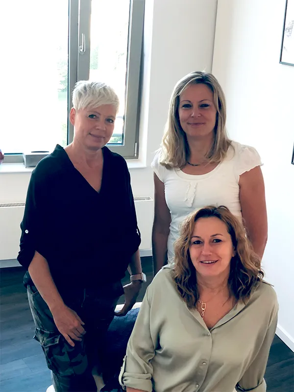 Drei Therapeutinnen aus dem Lenergo-Team in einem hellen Behandlungsraum